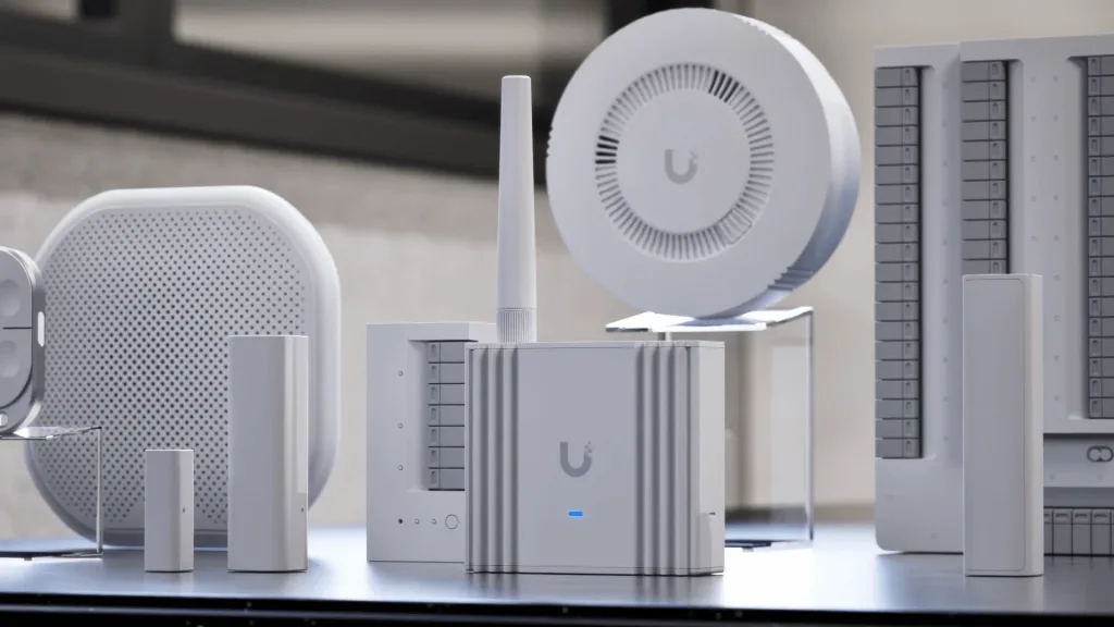 UniFi SuperLink átjáró, nyitásérzékelők, sziréna és füstérzékelő egy asztalon